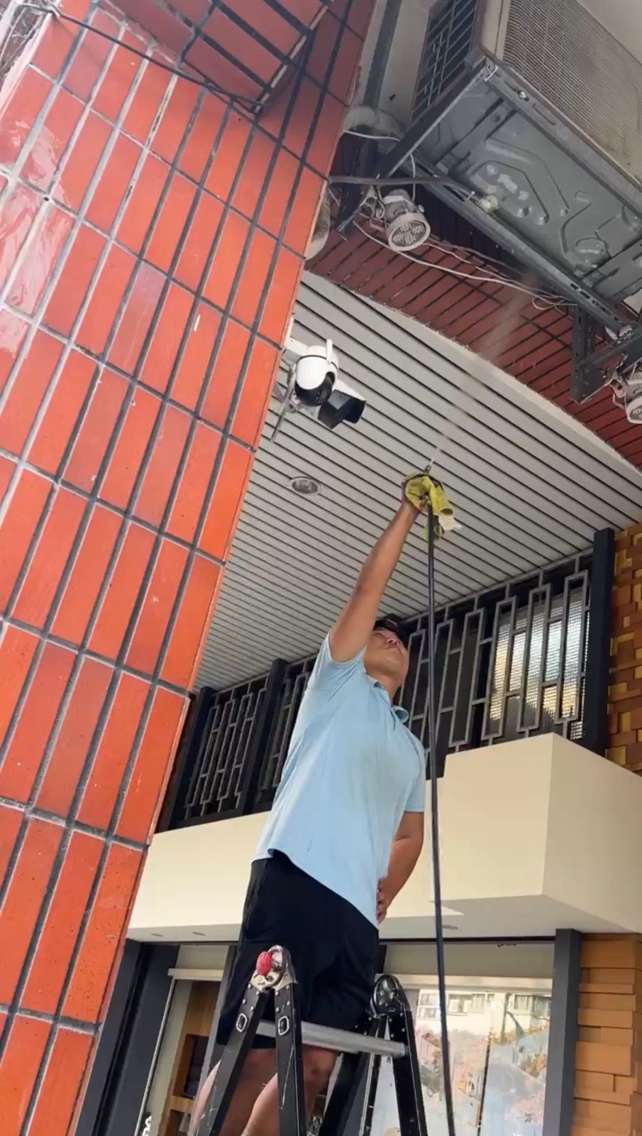 台中冷氣清洗 冷淨億點 工作室騎樓的室外機，師傅站上梯子用水柱沖